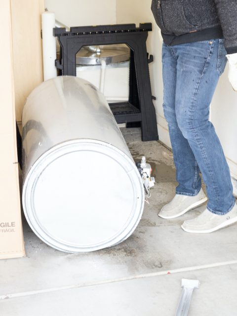 Old leaky water heater on the garage floor to be disposed of